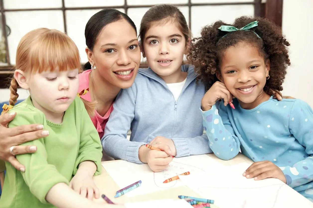 A group of children sitting around a table with crayons.