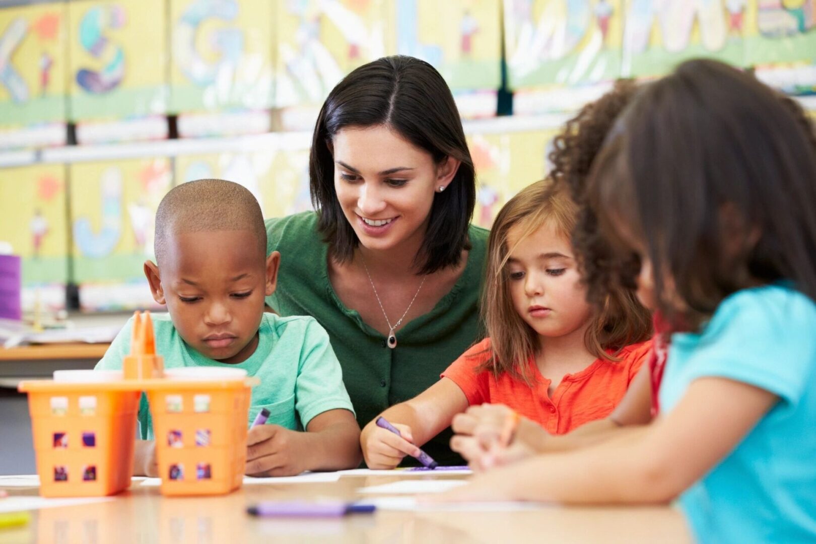 A woman is helping children with their writing.