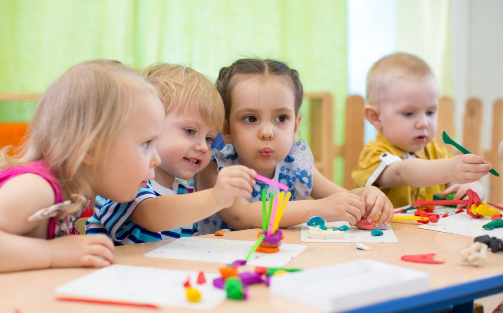 A group of children sitting at a table with some toys.