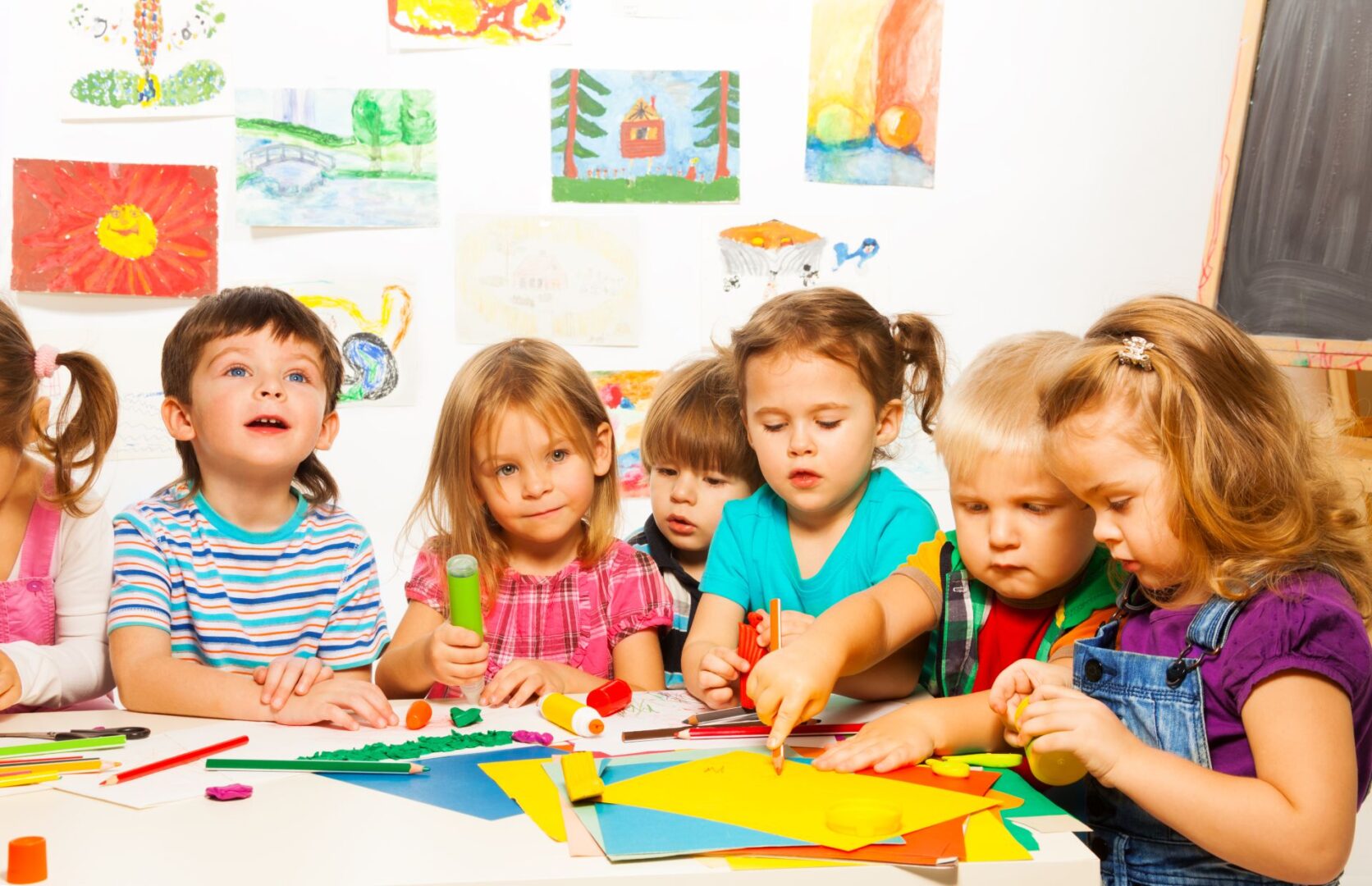 A group of children sitting at a table with paper.