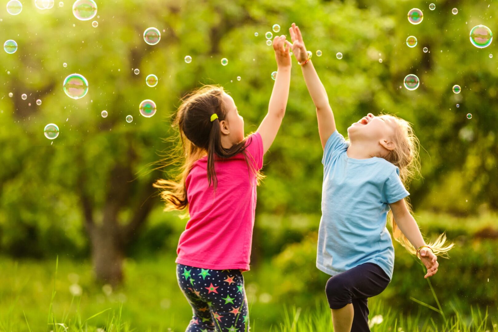 Two children playing with bubbles in a field.